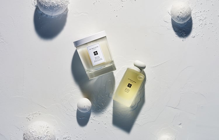 orange bitters 100ml cologne & home candle surrounded by snowballs and on a bed of white snow. 